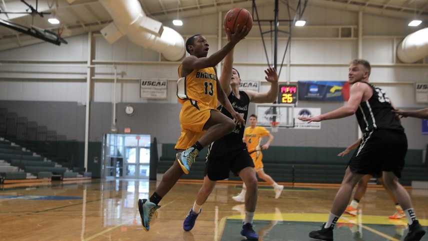Glenn Butler driving in for a layup in front of two defenders.
