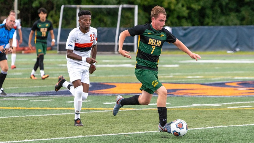 Daniel Prendergast (#7) moving the ball up the field with an opposing player chasing behind him.)