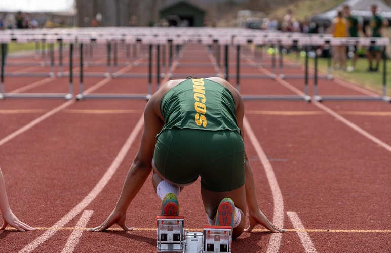 A SUNY Delhi hurdler positioned to begin a race. 
