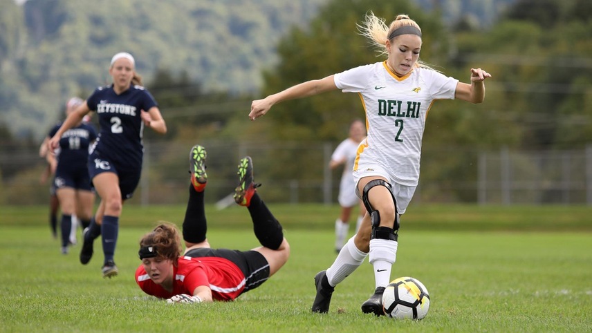 Kelsey Innes passes by the diving goalkeeper with the ball.