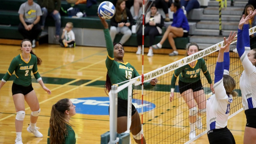 Witchney Clersainville pushing a ball over the net against two blockers.
